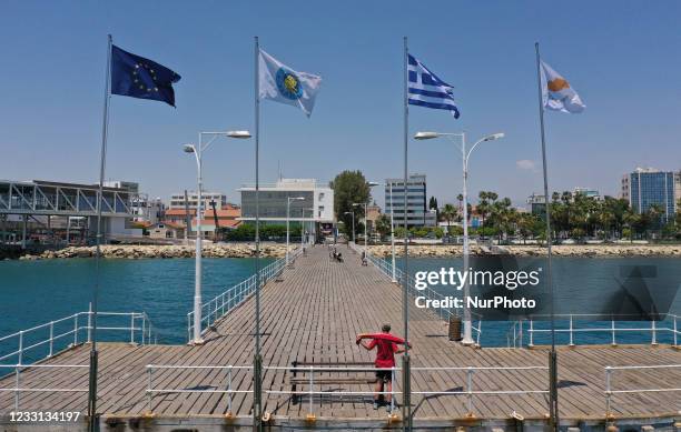 Man towels off after swimming on a pier with flags of the EU, Limassol, Greece and Cyprus in the Mediterranean port of Limassol. Cyprus, Thursday,...