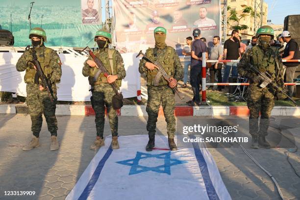 Members of the Ezz-Al Din Al-Qassam Brigades, the armed wing of the Hamas movement, stand on an Israeli flag during a military parade in a street in...