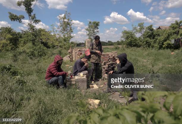 Group of migrants rest in a field near the Serbian village Majdan, close to the Hungary and Romania borders, on May 21, 2021. Inside an abandoned...