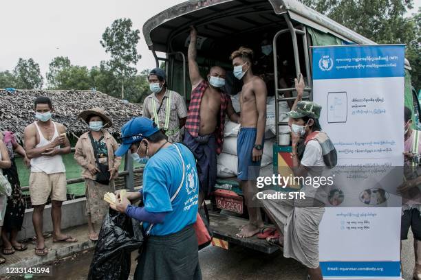 In this photo taken on May 21 people wait to receive bags of rice distributed by the World Food Programme as part of food aid efforts to support...