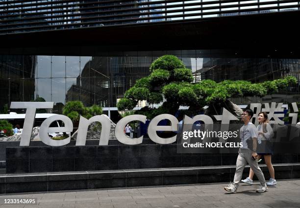 This photo taken on May 26, 2021 shows people walking past the Tencent headquarters in the southern Chinese city of Shenzhen, in Guangdong province.