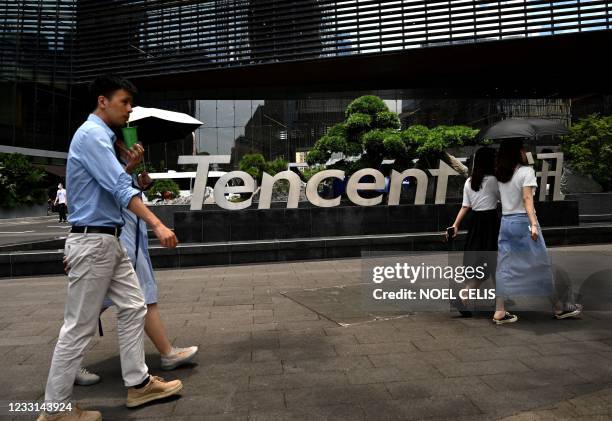 This photo taken on May 26, 2021 shows people walking past the Tencent headquarters in the southern Chinese city of Shenzhen, in Guangdong province.