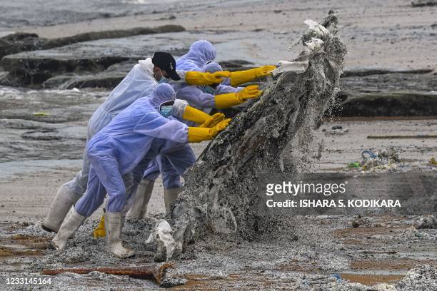 Sri Lankan Navy soldiers work to remove debris washed ashore from the Singapore-registered container ship MV X-Press Pearl, which has been burning...