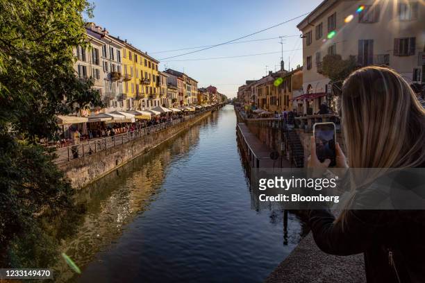 Tourist takes a photo of a canal in the Navigli neighborhood while full of people in Milan, Italy, on Thursday, May 27, 2021. Italy has approved a...