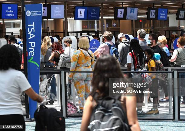 Travelers wait in line at a Transportation Security Administration screening checkpoint at Orlando International Airport on the Friday before...