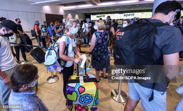 Travelers wait in line to check in at the Spirit Airlines ticket counter at Orlando International Airport on the Friday before Memorial Day. As more...