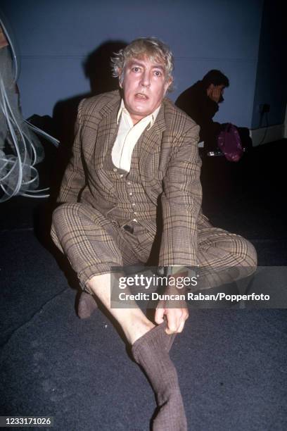 English satirist and comedic actor Peter Cook pulling his socks on, circa 1993.