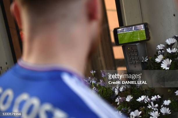 Chelsea supporter watches the game on his mobile phone in the street during the UEFA Champions League final football match between Manchester City...