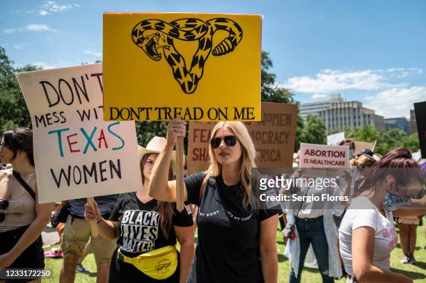 Protesters hold up signs at a protest outside the Texas state capitol on May 29, 2021 in Austin, Texas. Thousands of protesters came out in response...