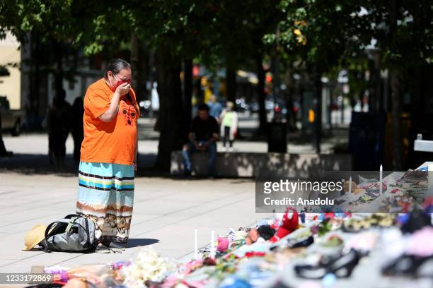 Woman mourns over 215 pairs of kids shoes outside Vancouver Art Gallery during a memorial on May 29, 2021 in Vancouver, British Columbia, Canada The...
