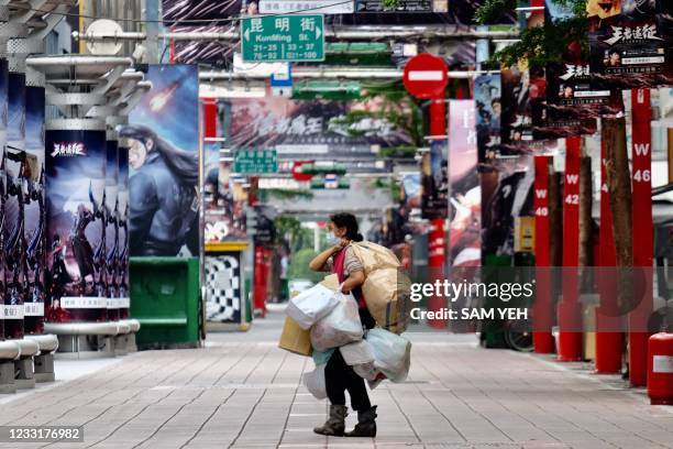 Woman carries her belongings as she walks on a street in Ximen, a commercial zone at the Wanhua District in Taipei on May 30, 2021.