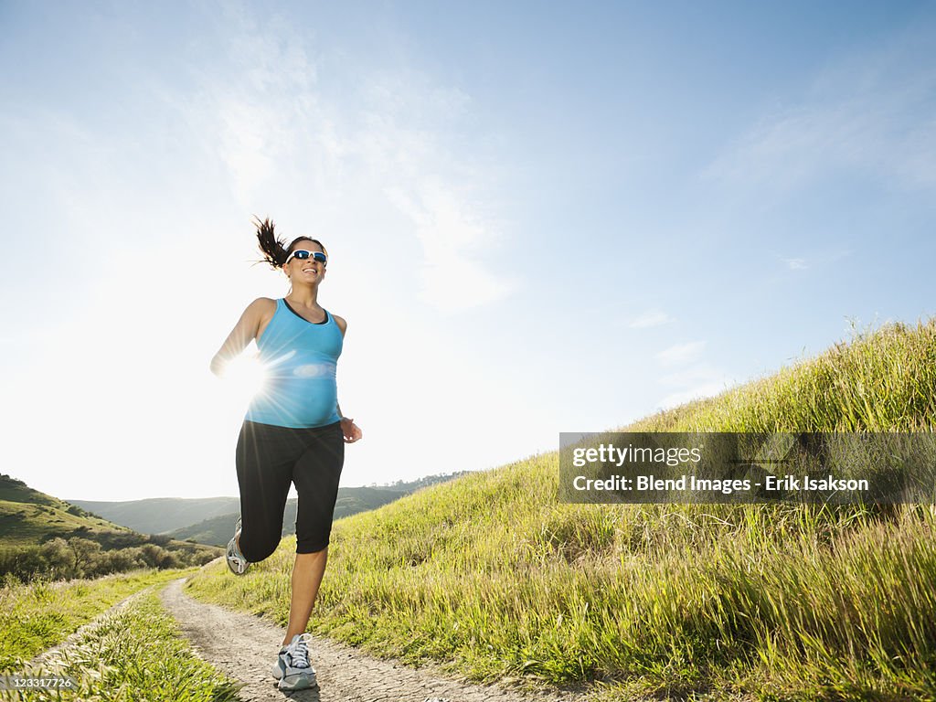 Pregnant Hispanic woman running in remote area