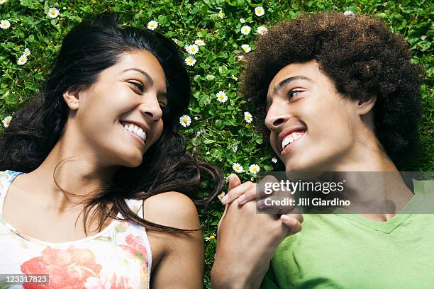 teenage couple laying in grass holding hands - casal adolescente imagens e fotografias de stock