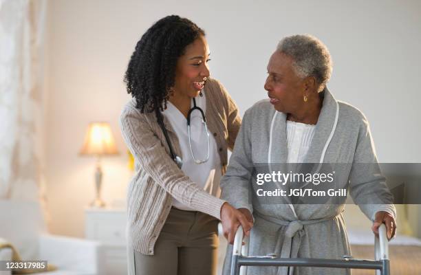 nurse helping woman walk with walker - african nurse stock pictures, royalty-free photos & images