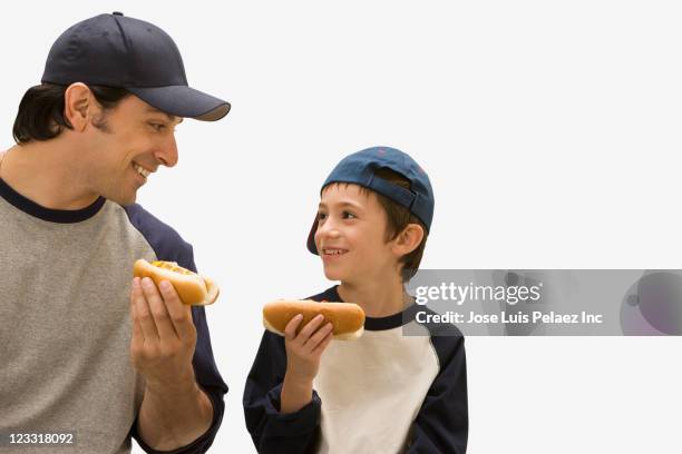 caucasian father and son eating hot dogs - baseball food stock pictures, royalty-free photos & images