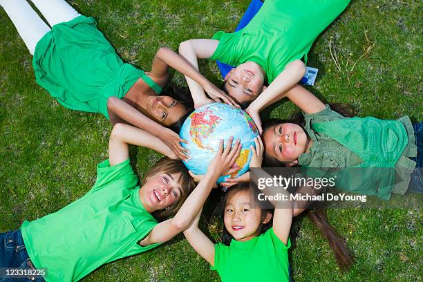 children laying in grass around globe - international day eight imagens e fotografias de stock