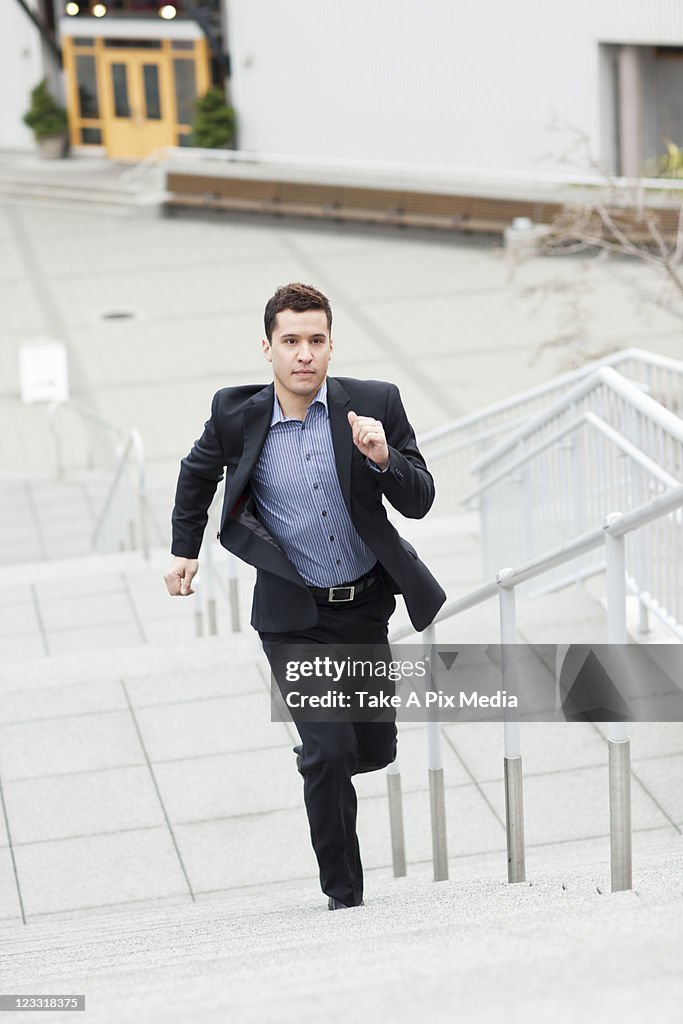 Mixed race businessman running up stairs