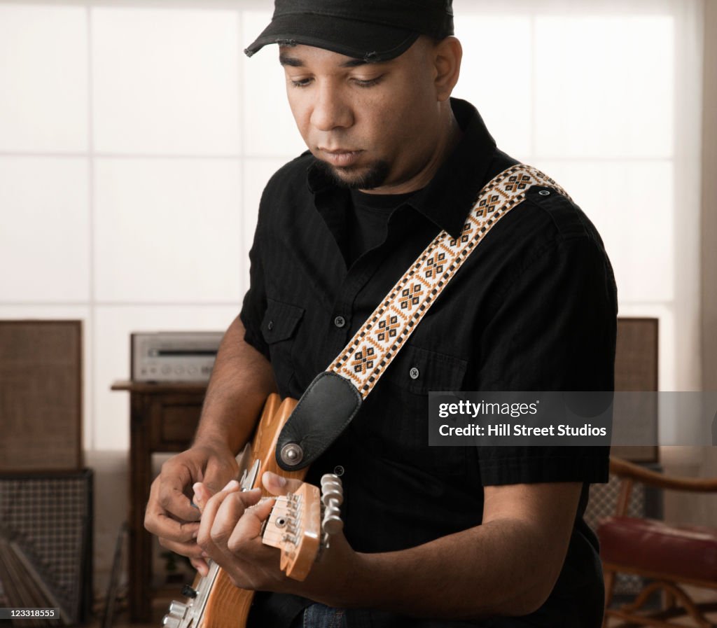 Mixed race man playing electric guitar