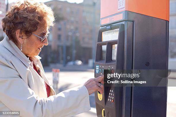 senior hispanic woman using parking meter - parquímetro imagens e fotografias de stock