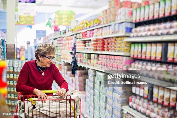 senior hispanic woman shopping in grocery store - seniors shopping stock pictures, royalty-free photos & images