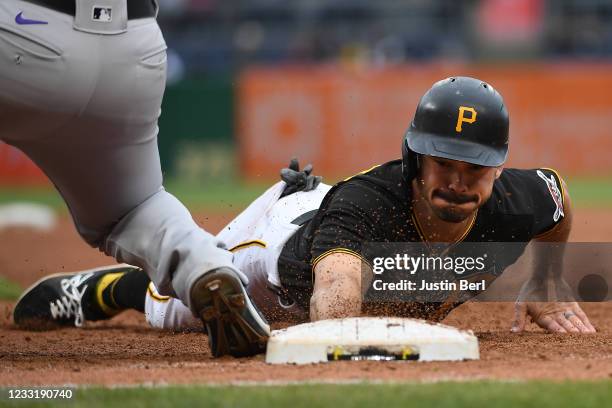 Bryan Reynolds of the Pittsburgh Pirates slides safely back to first base after a pickoff attempt by Daniel Bard of the Colorado Rockies in the...