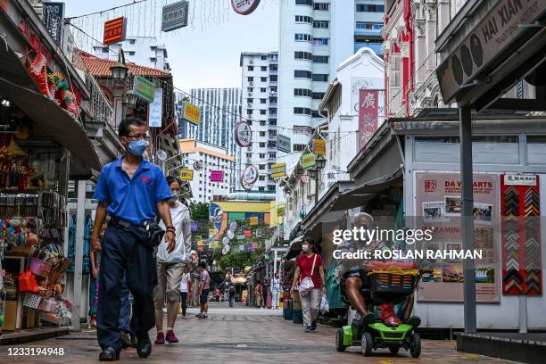 People walk along an alley lined with commercial stalls in Chinatown district in Singapore on May 31, 2021.