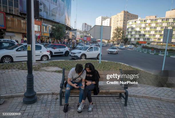 An Iranian man and a woman use a smartphone while sitting on a street-side in downtown Tehran on May 28, 2021. Iranians will vote to elect the new...
