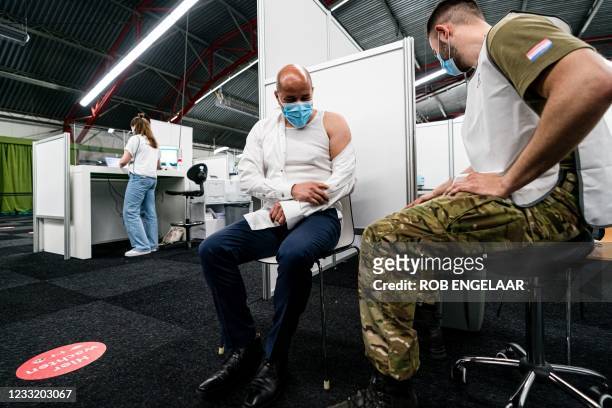 Dutch Mayor of Arnhem Ahmed Marcouch is vaccinated by a serviceman at the Covid-19 vaccination site in Molenbeke, Arnhem, on May 31, 2021. - Defense...