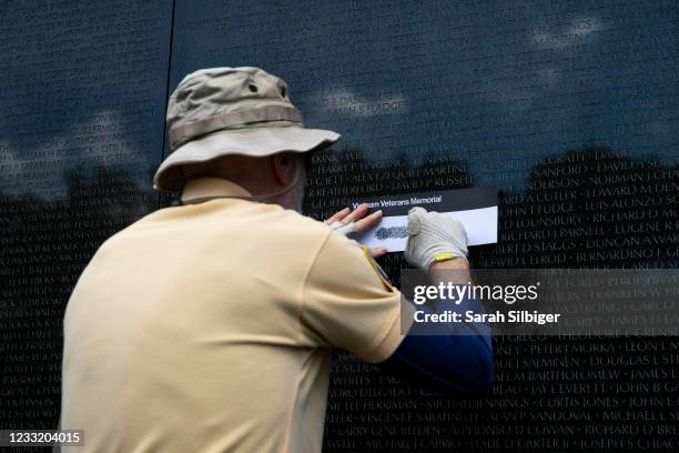 Man creates a rubbing of an engraved name during Memorial Day events at the Veterans Memorial on the National Mall on May 31, 2021 in Washington, DC.