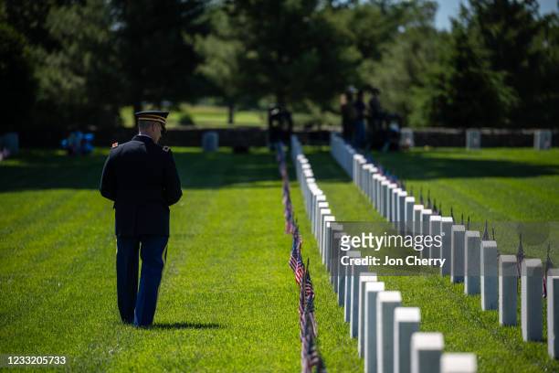 Military service member walks along a row of graves and American flags before a Memorial Day ceremony in the Fort Knox Main Post Cemetery on May 31,...