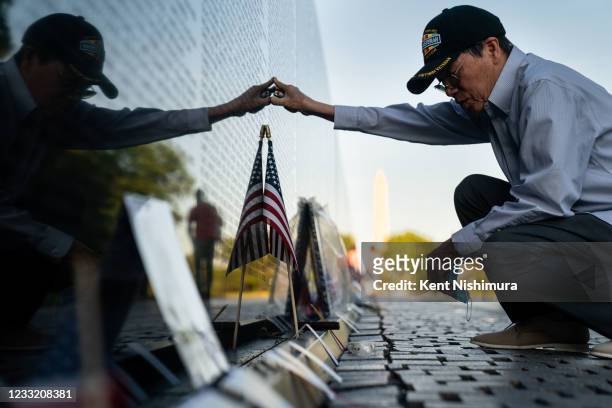 Quyen Pham, of Newport News, Va., pauses after placing a lit cigar at the base of the marble wall of the Vietnam Veterans Memorial to pay his...