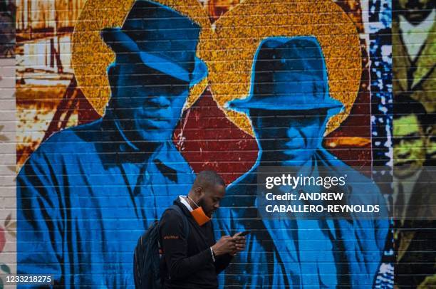 Man checks his phone next to a mural in the Greenwood district on the 100th anniversary of the 1921 Tulsa Massacre in Tulsa, Oklahoma on June 1,...