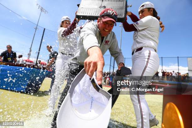 Head coach Michael Mook of the West Texas A&M Buffs receives a celebratory ice bath from his players after defeating Biola Eagles in game 3 of the...