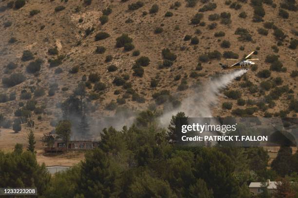 Firefighting helicopter drops water towards a burning house of a suspected gunman of a shooting at a fire station on June 1, 2021 in Acton,...