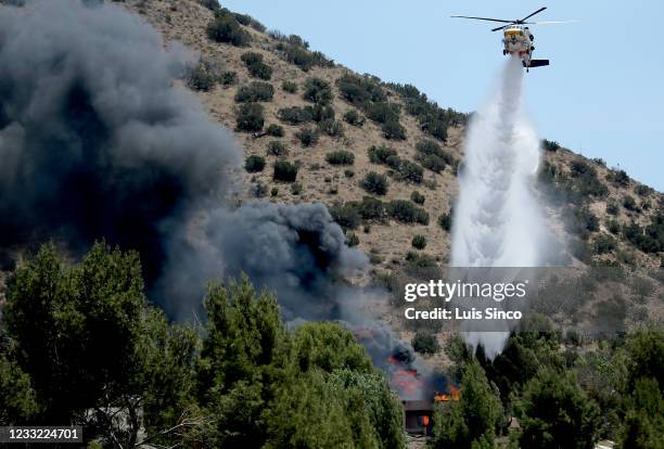 Helicopter makes a water drop on a burning house in Acton where a suspect in a shooting was believed to be barricaded on Tuesday, June 1, 2021. The...