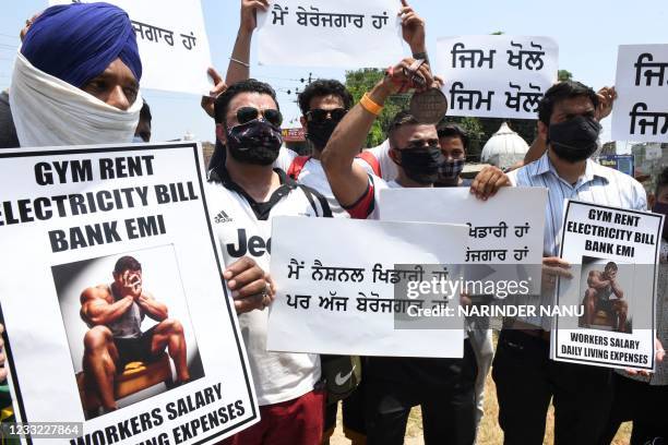 Gym owners and trainers hold placards as they stage a protest demanding the government to reopen their fitness centers, during a lockdown imposed to...