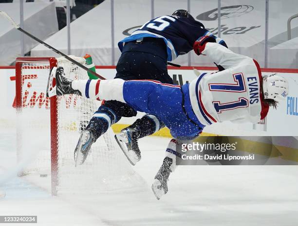 Jake Evans of the Montreal Canadiens is checked hard by Mark Scheifele of the Winnipeg Jets after Evans's third-period empty-net goal in Game One of...