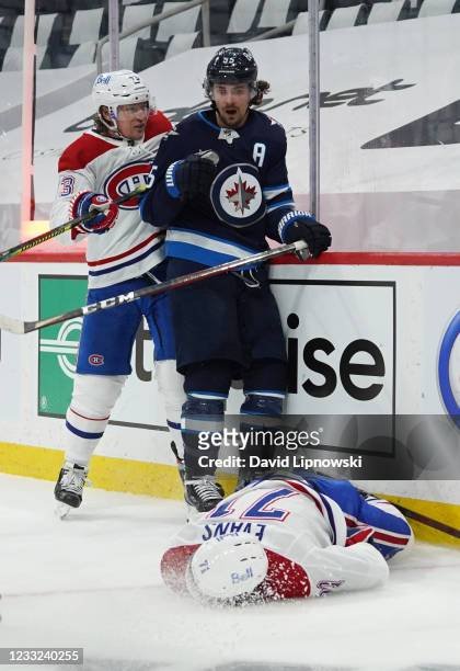 Jake Evans of the Montreal Canadiens lies on the ice injured from a hard check by Mark Scheifele of the Winnipeg Jets after Evans's third-period...