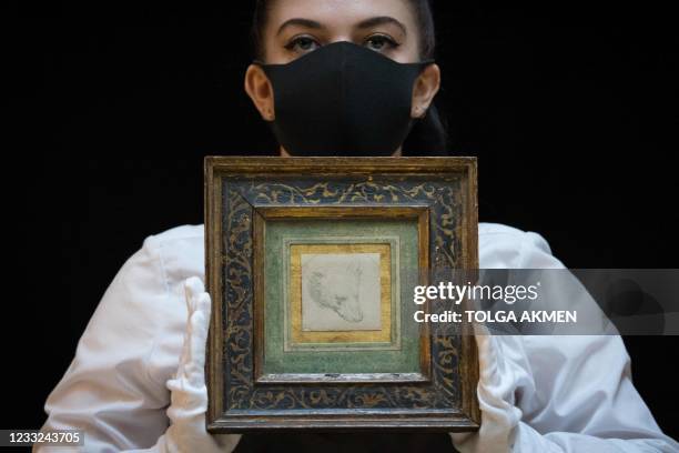 Gallery employee poses with a drawing by Italian polymath Leonardo da Vinci entitled 'Head of a Bear' during a photocall at Christies auction house...