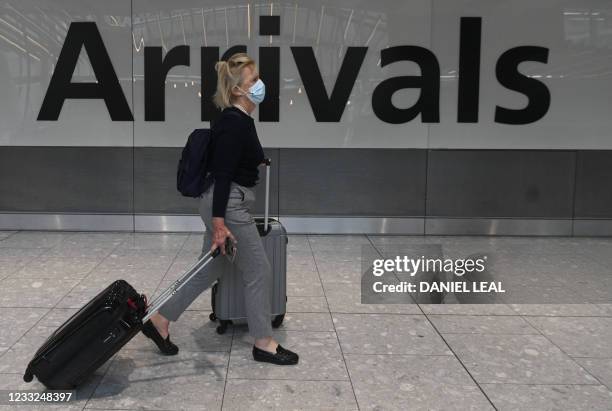 Pasenger pulls her roller suitcase on arrival in Terminal 5 at Heathrow airport in London, on June 3, 2021. - Health Secretary Matt Hancock has said...