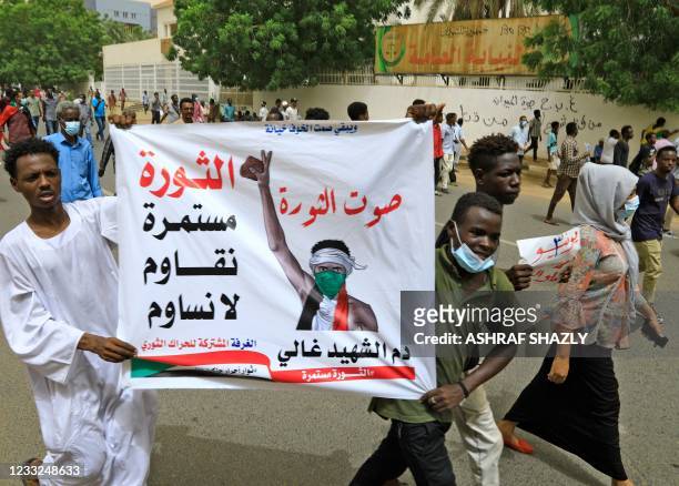 Sudanese protesters hold a banner that reads in Arabic: "The Revolution is continuing, we resist and we wont compromise," in capital Khartoum, on...