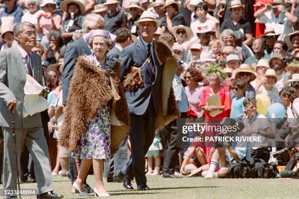 Queen Elizabeth II and her husband Duke of Edinburgh wearing a traditional cloak arrive at the Waitangi National Marae where the queen marked the...