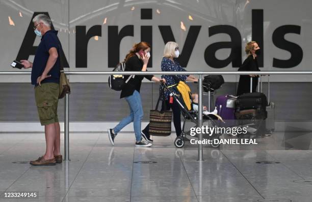Passengers push their luggage on arrival in Terminal 5 at Heathrow airport in London, on June 3, 2021. - Health Secretary Matt Hancock has said it...
