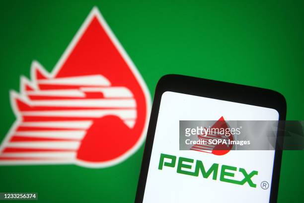 In this photo illustration, a Pemex logo is seen on a smartphone and a pc screen in the background.