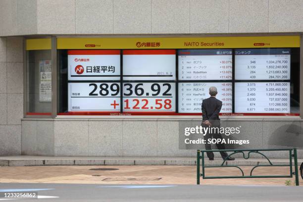 Businessman looks at an electronic stock exchange board showing the Nikkei 225 index in central Tokyo.