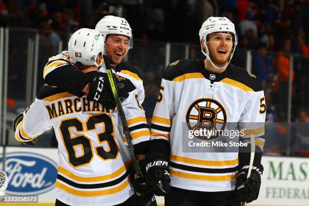 Brad Marchand of the Boston Bruins is congratulated by Charlie McAvoy and Jeremy Lauzon after scoring the game-winning goal in overtime to defeat the...