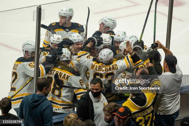 The Boston Bruins players mob Boston Bruins Center Brad Marchand to celebrate his game winning goal during the overtime period of Game 3 of the NHL...