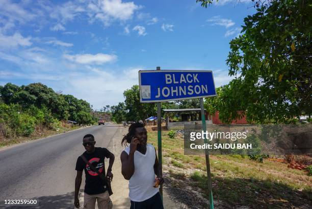 Residents of Black Johnson village walks past a sign on May 12, 2021. - Sierra Leoneans are protesting a planned industrial harbour in a lush village...