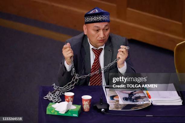 Witness Kazakh-Uyghur Omir Bekali demonstrates how he says he was shackled in chains at a re-education camp as he speaks on the first day of hearings...