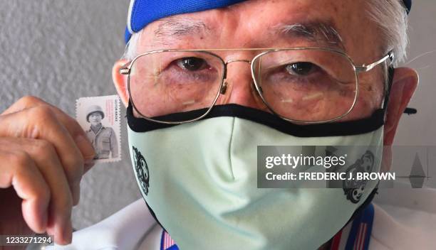 World War 2 US military veteran who served in the 442nd Regimental Combat Team, Yosh Nakamura displays the latest US postage stamp, "Go For Broke:...